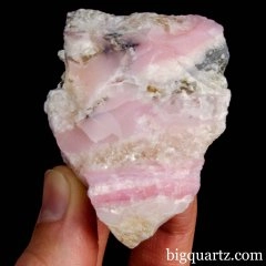 Small common pink opal specimen being held by a hand