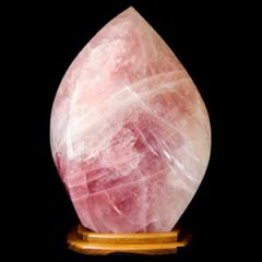 Large pink rose quartz crystal sculpture in the shape of a flame