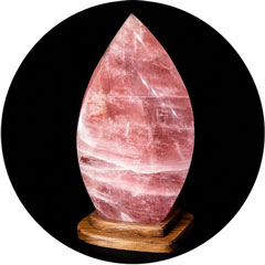 Large pink rose quartz crystal sculpture in the shape of a flame